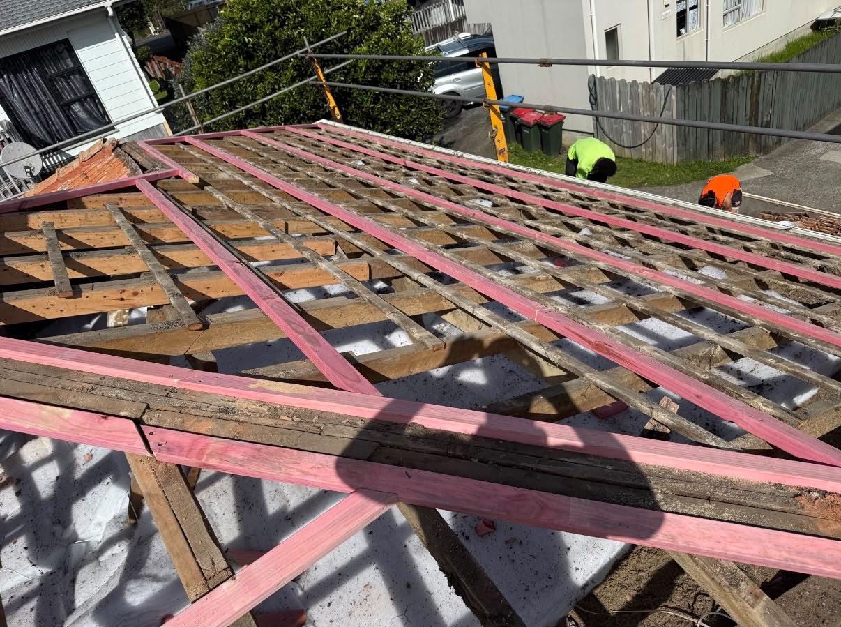 A stripped roof with new treated battens laid over the old framing, the yard below cleared for the strip-out