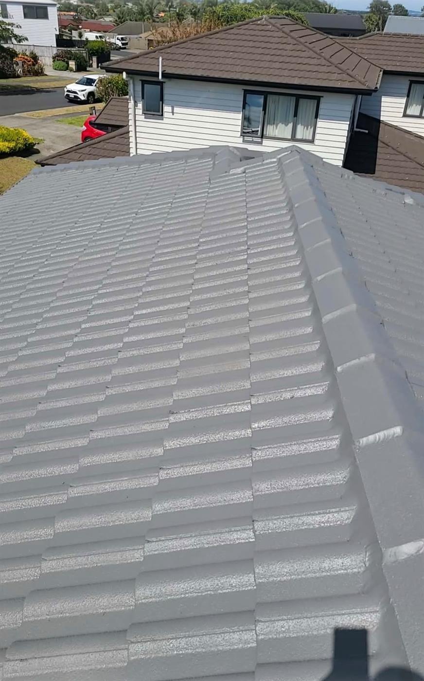 A completed concrete tile roof restoration in light grey, seen across the ridge